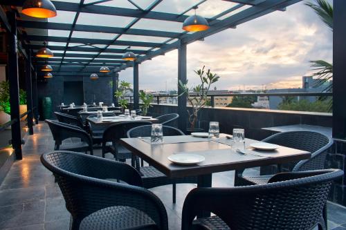 restauracja ze stołami i krzesłami na balkonie w obiekcie President Hotel w mieście Mysuru