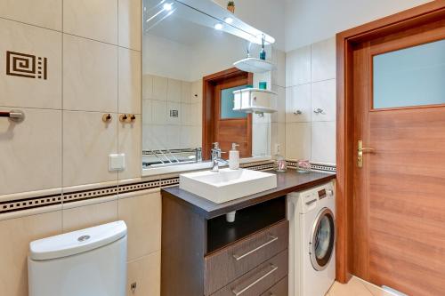 a bathroom with a sink and a washing machine at Wave Apartments - Lastadia Relax in Gdańsk