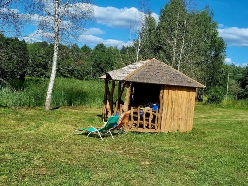 einen Stuhl und einen Pavillon auf einem Feld in der Unterkunft A&G Sodyba camp ąžuolų pavėsyje in Plungė