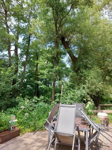 a group of chairs sitting on a deck with trees at Schöne Wohnung direkt am Bach in Neunkirchen am Sand