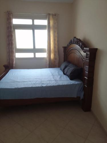 1 dormitorio con cama de madera y ventana en golden land en Sharjah