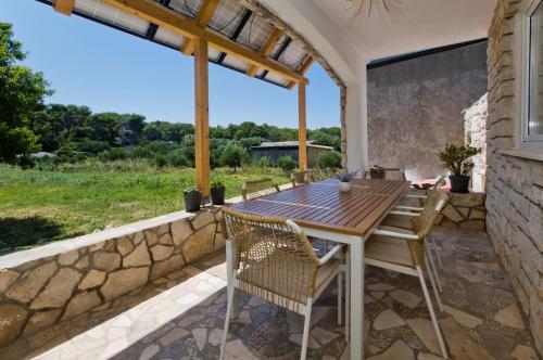 an outdoor patio with a wooden table and chairs at Robinson house T'n'T in Hvar