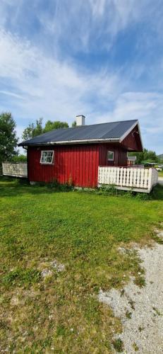 a red barn with a white fence in a field at Bungalåven Lodge AS in Børselv