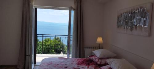 a bedroom with a bed and a door to a balcony at Apartments Villa Elma in Mošćenička Draga
