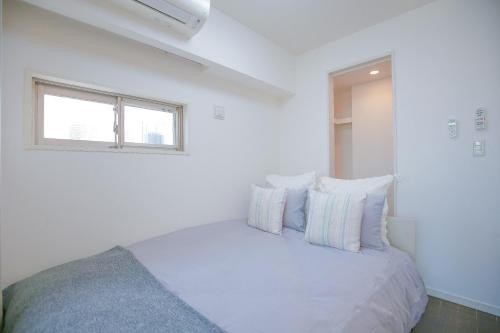 - une chambre blanche dotée d'un lit avec oreillers et d'une fenêtre dans l'établissement 10min walk to Shinjuku YEoE-2, à Tokyo