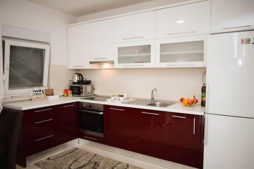 uma cozinha com armários vermelhos e um lavatório em Apartman Villa Vita em Capljina