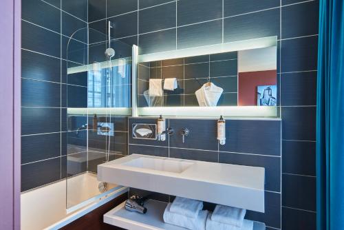 a bathroom with a sink and a mirror and blue tiles at Mercure Paris Tour Eiffel Pont Mirabeau in Paris