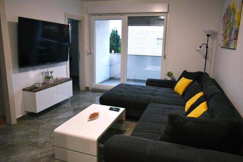 a living room with a black couch and a tv at Brand new, luxury apartment SOL-Inn near Split with parking in Solin