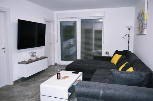 a living room with a black couch and a tv at Brand new, luxury apartment SOL-Inn near Split with parking in Solin