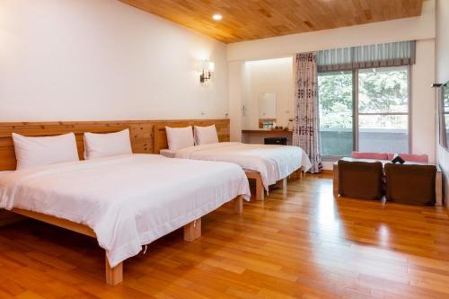 twee bedden in een kamer met houten vloeren bij Hou Shan Ren Jia B&B Hall A in Yung-an-ts'un
