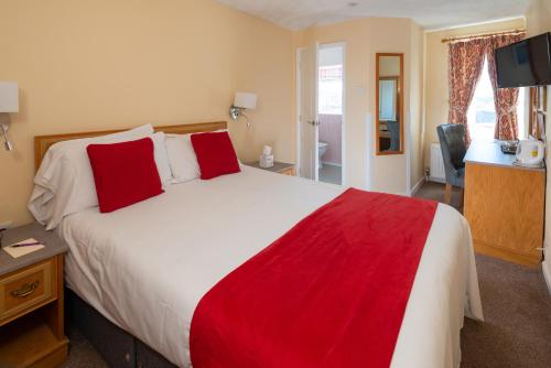 a bedroom with a large bed with red pillows at Hotel Rex in Weymouth