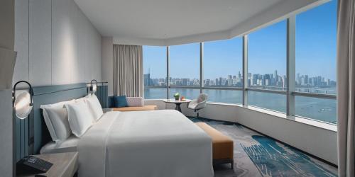Crowne Plaza Hangzhou Riverside, an IHG Hotel في هانغتشو: غرفة فندقية بسرير كبير ونافذة كبيرة
