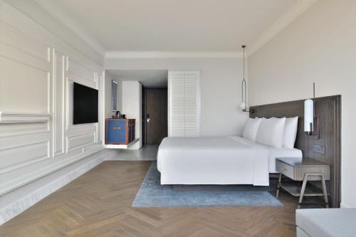 a white bedroom with a bed and a tv at Le Meridien Amritsar in Amritsar