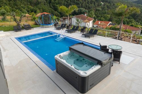 uma piscina com banheira de hidromassagem ao lado de uma casa em Quinta Flor de Lis, Gerês em Vieira do Minho