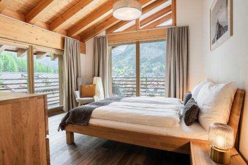a bedroom with a bed and a large window at Fantastic panoramic view home in Zermatt in Zermatt