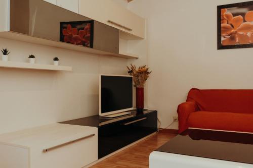 a living room with a red couch and a television at La Dolce Vita Cittadella in Pitigliano
