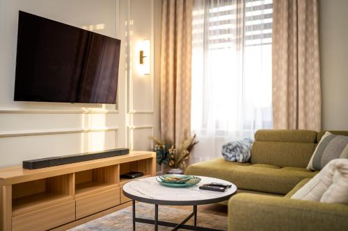 - un salon avec une télévision, un canapé et une table dans l'établissement Apartamenty Poznańska 15, à Inowrocław