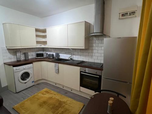 a small kitchen with white cabinets and a washer and dryer at Ground Floor Two Bed Cairo Street in Warrington