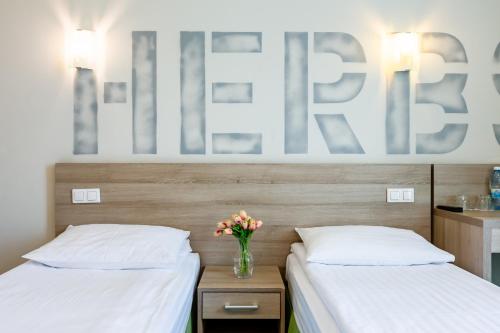 two beds in a room with a vase of flowers at PracticOtel in Kyiv