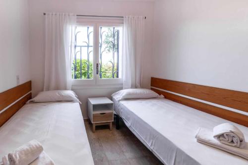deux lits dans une chambre avec une fenêtre dans l'établissement Cau del Llop 70 - Bonito apartamento con jardín, à Llançà