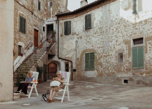 two older women sitting in chairs outside of a building at La Dolce Vita Cittadella in Pitigliano