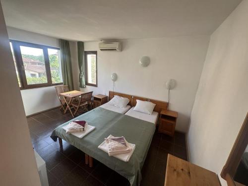 a hotel room with a bed and a table and a window at Guest House Karavida in Sinemorets