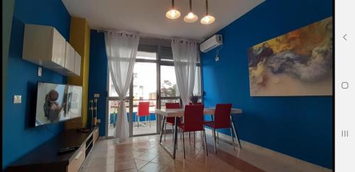 uma sala de jantar com paredes azuis e uma mesa com cadeiras vermelhas em ADRIATIC Seaview Apartments em Durrës