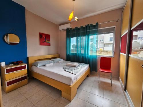 um pequeno quarto com uma cama e uma cadeira vermelha em ADRIATIC Seaview Apartments em Durrës