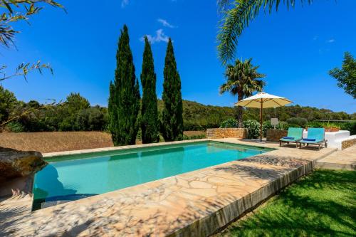a swimming pool with two chairs and an umbrella at Villa Can Curreu in Sant Carles de Peralta
