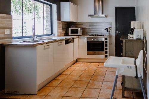 une cuisine avec des armoires blanches et un évier dans l'établissement Maison Madeleine, à La Flèche