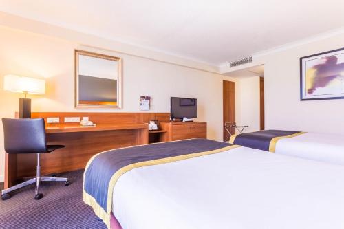 a hotel room with two beds and a desk at Holiday Inn Newcastle Gosforth Park by IHG in Newcastle upon Tyne