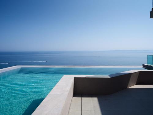 a swimming pool with the ocean in the background at Bardo Villa, Endless Blue with Heated Pool, By ThinkVilla in Argasi