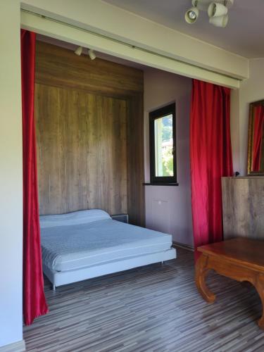 um quarto com uma cama com cortinas vermelhas e uma mesa em Camera Aminta - Casa Aminta em Valtesse