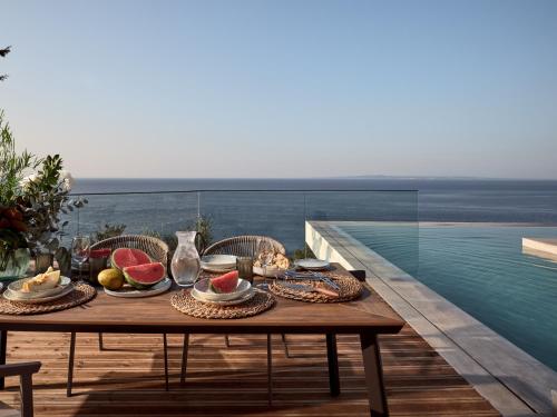 a table with food and watermelon on a balcony at Bardo Villa, Endless Blue with Heated Pool, By ThinkVilla in Argasi