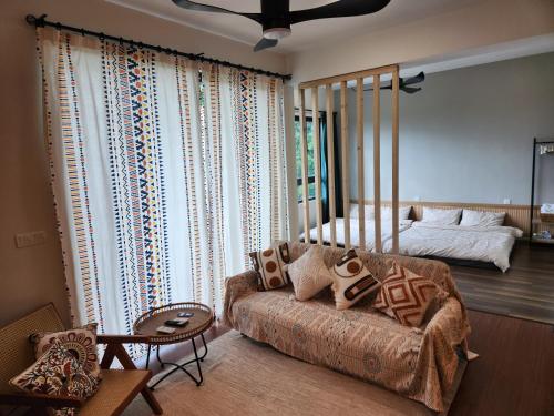 een woonkamer met een bank en een bed bij Unique Boho Style Condo with NETFLIX for up to 5PAX - Enjoy Mountain View while swimming at the Infinity Pool & Natural Hotspring Pool, 2mins walk to the Lost World of Tambun, Water Themepark at IPOH in Ipoh