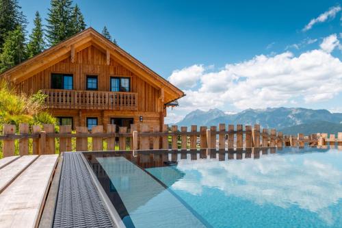 a log house with a swimming pool in front of it at Poolchalet Dachsteinblick in Pruggern