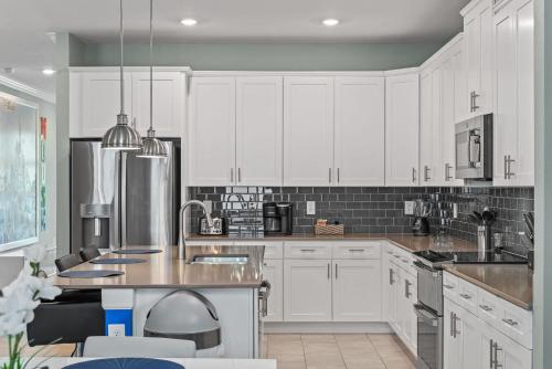 a kitchen with white cabinets and stainless steel appliances at Magical Themed Home - Disney 15 min in Kissimmee