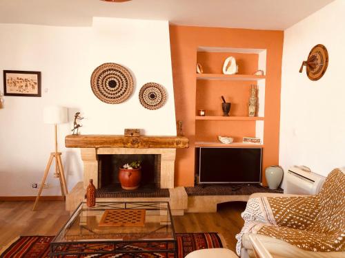 een woonkamer met een open haard en een televisie bij VILLA TAPÔA - Maison au coeur de Marseillan in Marseillan