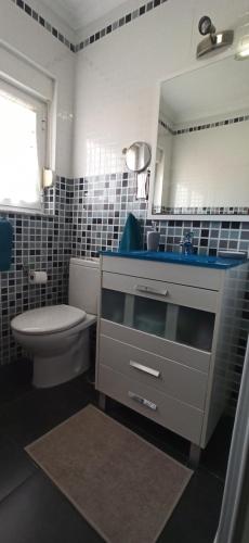 a bathroom with a sink and a toilet and a mirror at Apartamento El Pórtico de Muros in Muros de Nalón