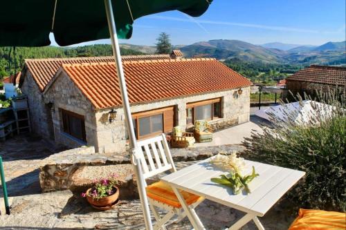 a small stone house with a table and an umbrella at ROSAS DA GRANJA - CASA DE CAMPO in Granja