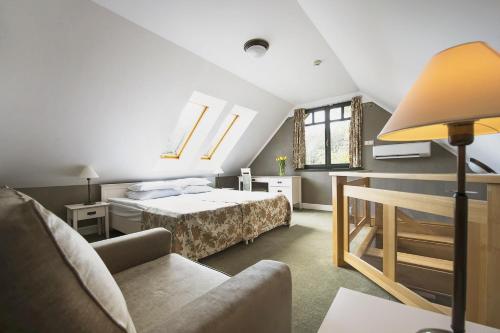 a bedroom with a bed and a couch and a chair at Warmia Park in Olsztyn