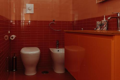 a red tiled bathroom with a toilet and a sink at Casa Caracciolo in Pitigliano