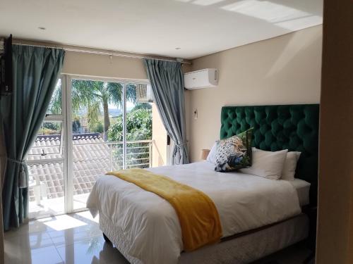 a bedroom with a large bed and a balcony at Malusi Bed and Breakfast in Verulam
