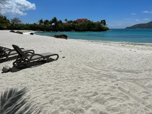 two lounge chairs on a beach with the ocean at Eden Island (GIE Apartment) in Eden Island