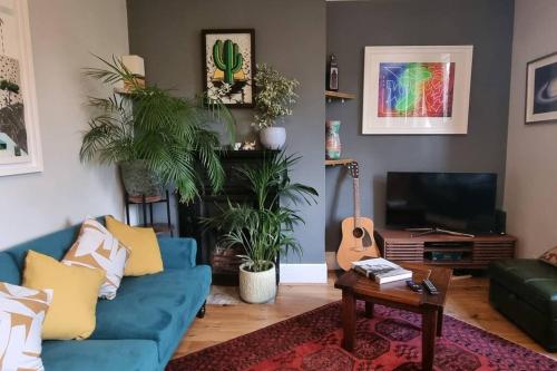 a living room with a blue couch and a guitar at Highgate Maisonette with Roof Terrace in London
