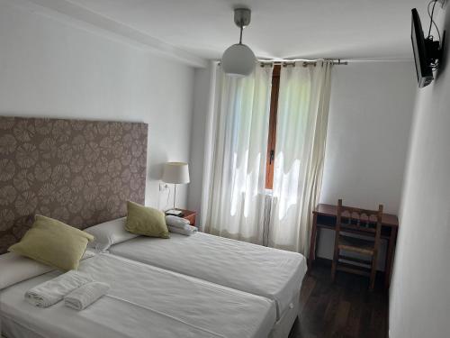 een slaapkamer met 2 bedden, een bureau en een raam bij badain in La Fortunada