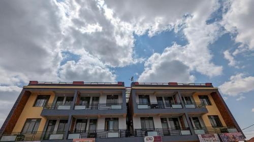 a tall building with a cloudy sky in the background at Star Max Apartments in Kigali