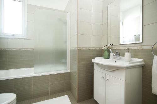 a white bathroom with a sink and a shower at Villa Danata in Protaras