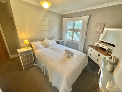 a bedroom with a white bed and a television at Garden Cottage - 3 Bedroom Close to Town and Beach in Bournemouth