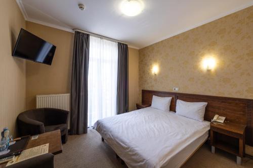 a hotel room with a bed and a desk and a television at Kamelot in Ternopilʼ